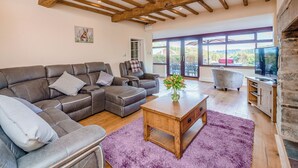 Una sala de estar con un sofá modular, una mesa de centro de madera y un televisor.