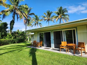 A house with a covered patio, wooden furniture, and palm trees. - Arnott's Lodge (Hilo)