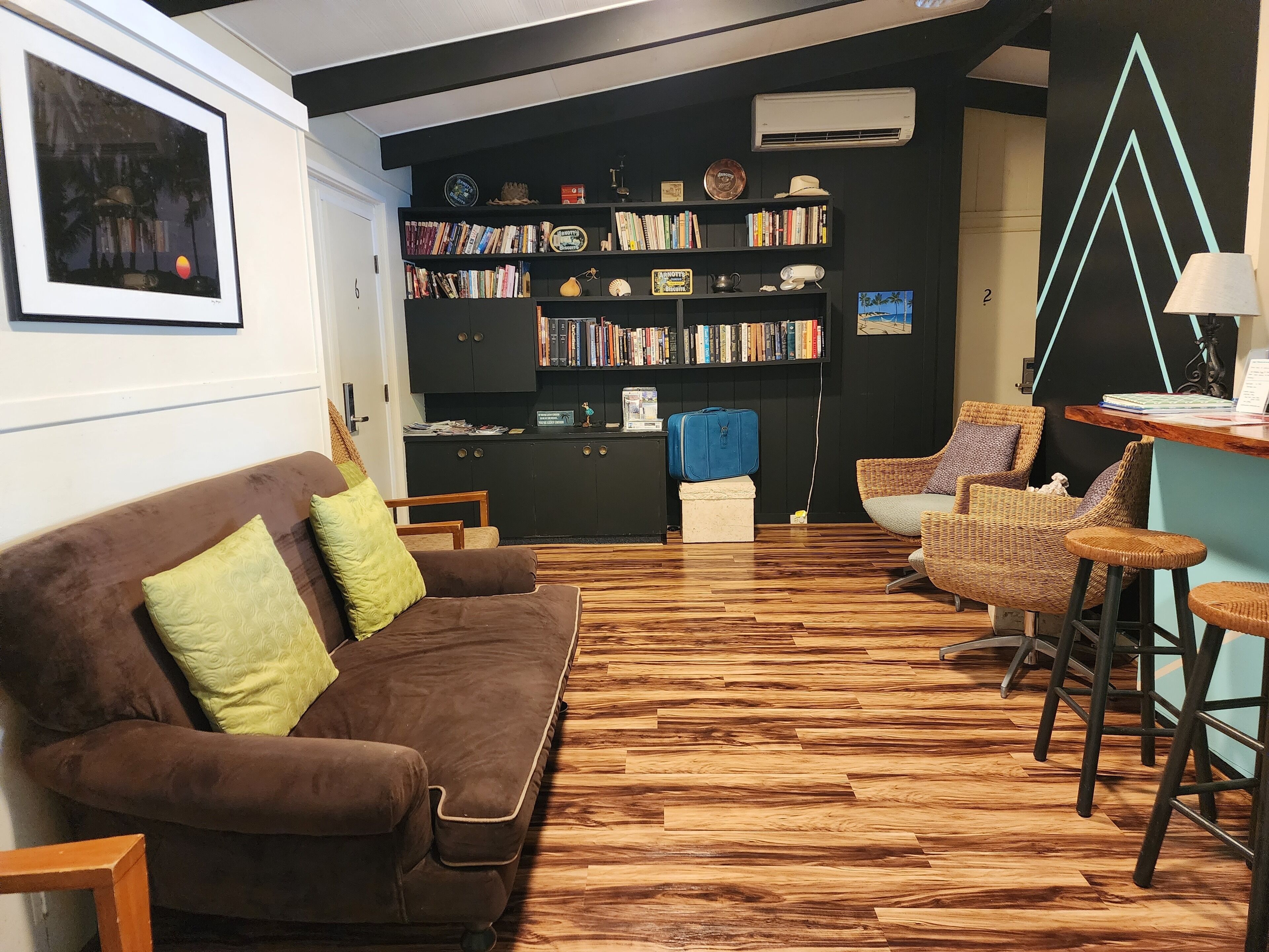 A cozy living area with a brown sofa, a bookshelf, and a bar area with stools.