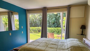 Ein Hotelzimmer mit Bett, Fenster, Stuhl und Tisch vor dem Balkon.