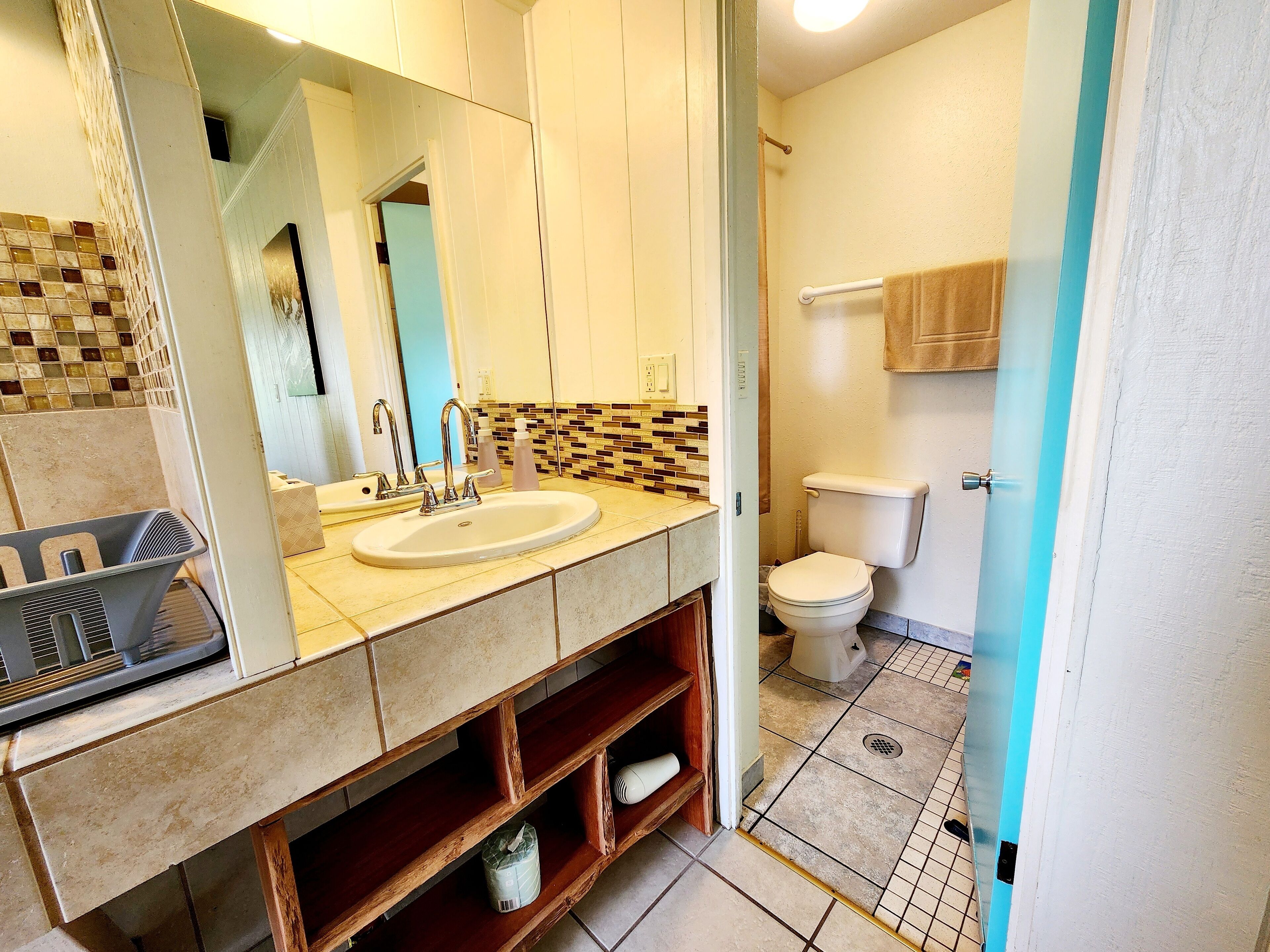A bathroom with a double sink, a toilet, and a mirror.