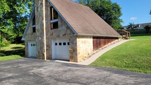 Un garage in pietra con tetto spiovente, un portone bianco e un recinto in legno.