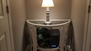 Un corridoio stretto con un tavolo consolle bianco, una lampada e una piccola pianta.