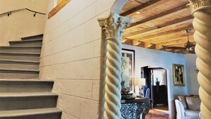 A staircase with stone walls and wooden beams, leading to a room with a desk and chair. - Casa Grandview Inn (West Palm Beach)