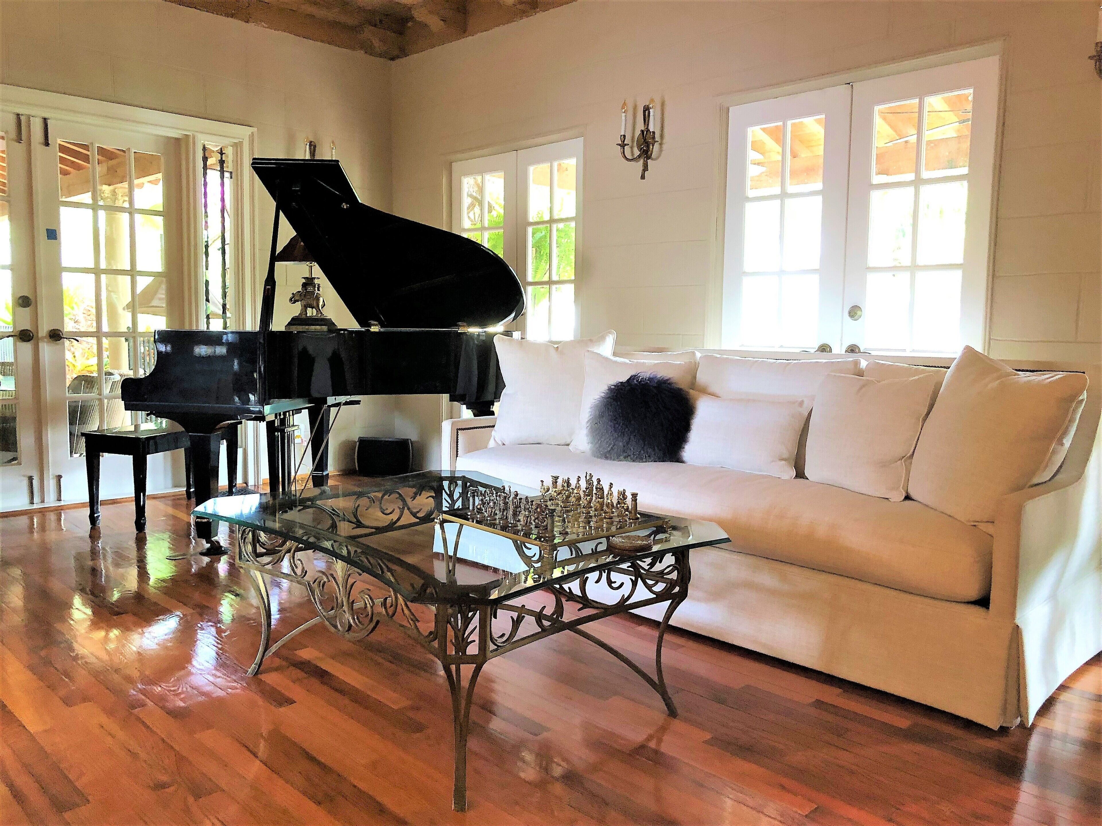 Un piano à queue dans une pièce spacieuse, avec un canapé blanc et une table basse en verre.