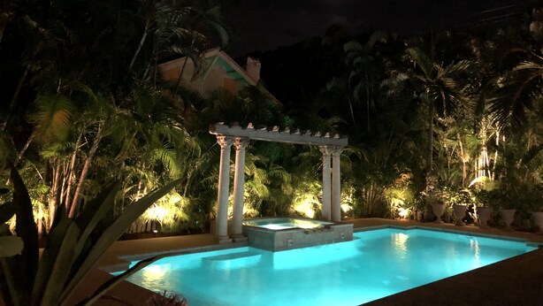 A nighttime pool area with a pergola, palm trees, and a moon in the sky. - Casa Grandview Inn (West Palm Beach)