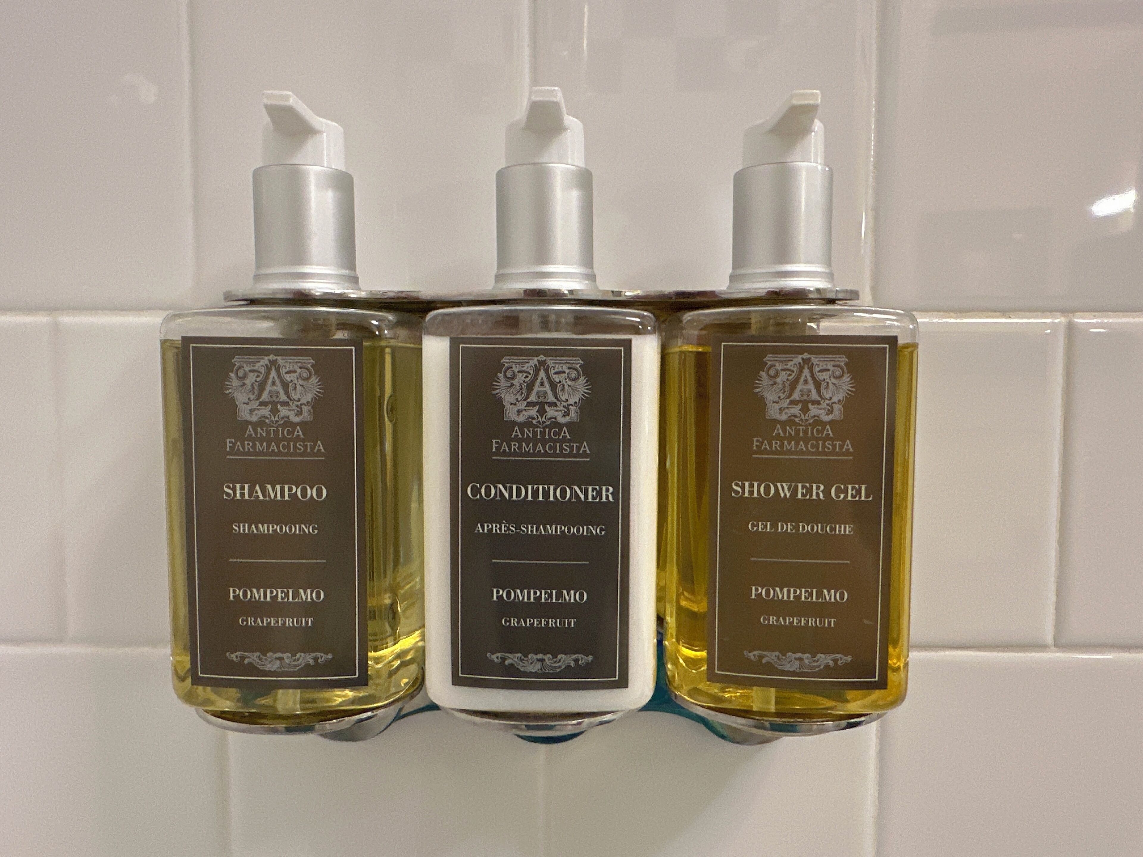 Tre flaconi di prodotti Antica Farmacista: Shampoo, Balsamo e Gel Doccia, tutti con l'etichetta 'Pompelmo Grapefruit'.