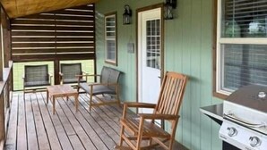 A covered porch with wooden flooring, a grill, and two rocking chairs. - Black Hills Farmhouse, Guest House #1 (Custer)