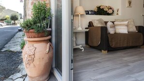 Uma sala de estar aconchegante com sofá, almofadas, abajur e planta em vaso perto de uma porta de vidro.