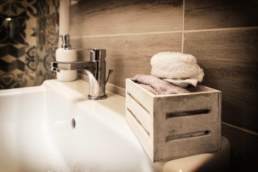 A bathroom with a sink, a towel holder, and a wooden box with towels.