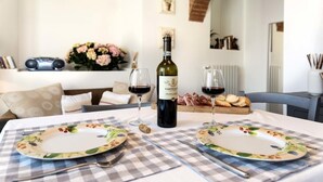 Uma mesa de jantar posta com dois pratos, copos de vinho e uma garrafa de vinho.