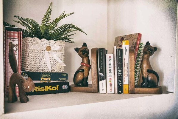 A shelf with a plant, books, and two cat-shaped bookends.