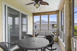 A covered patio with a table and chairs, a ceiling fan, and a view of neighboring houses.