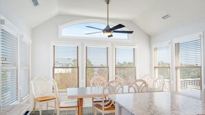 Una cocina con una isla grande, armarios blancos y un ventilador de techo.