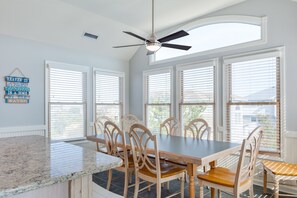 A dining area with a granite countertop, wooden chairs, and a ceiling fan.