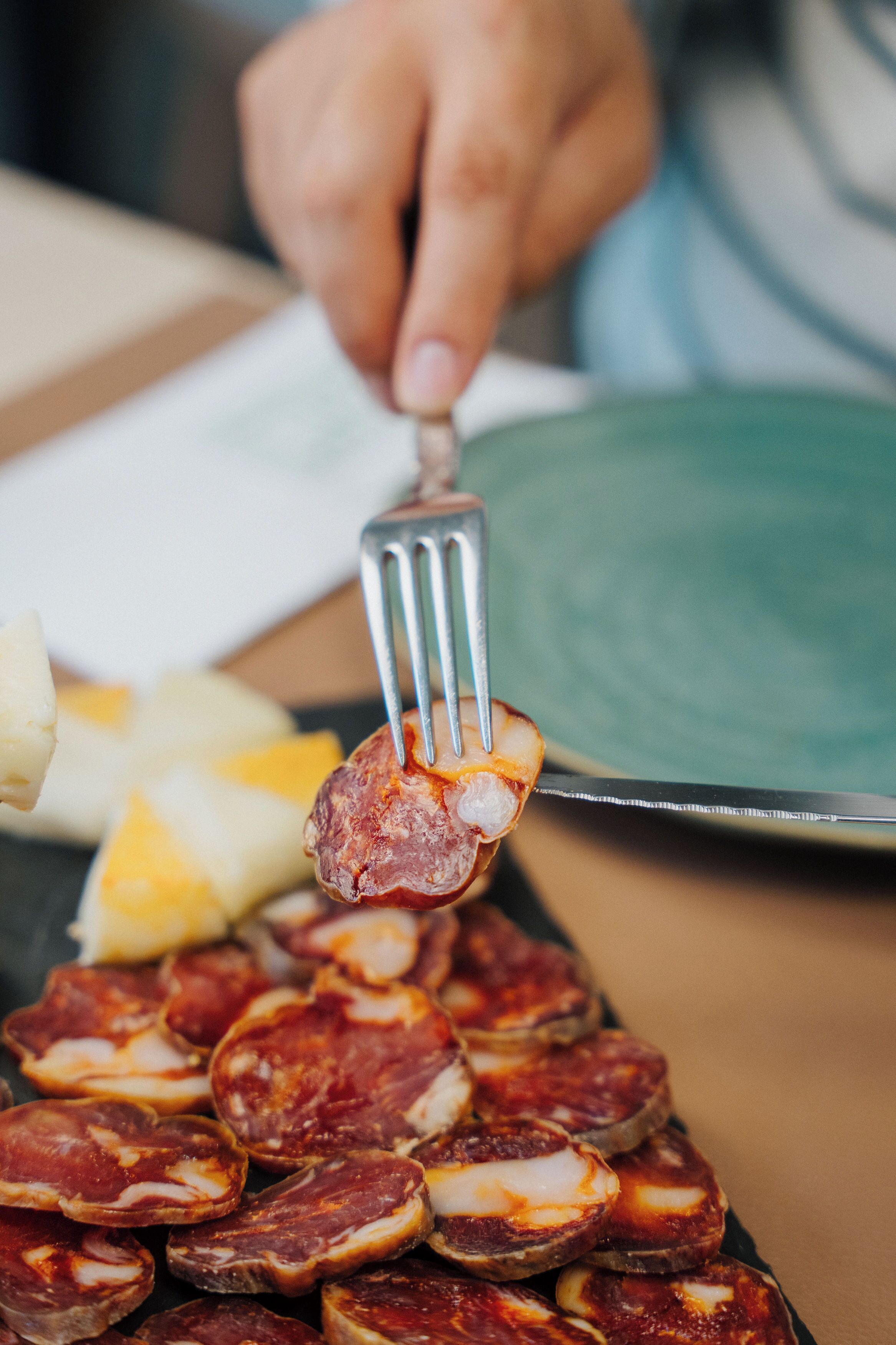 Una persona sosteniendo un tenedor con un trozo de carne.