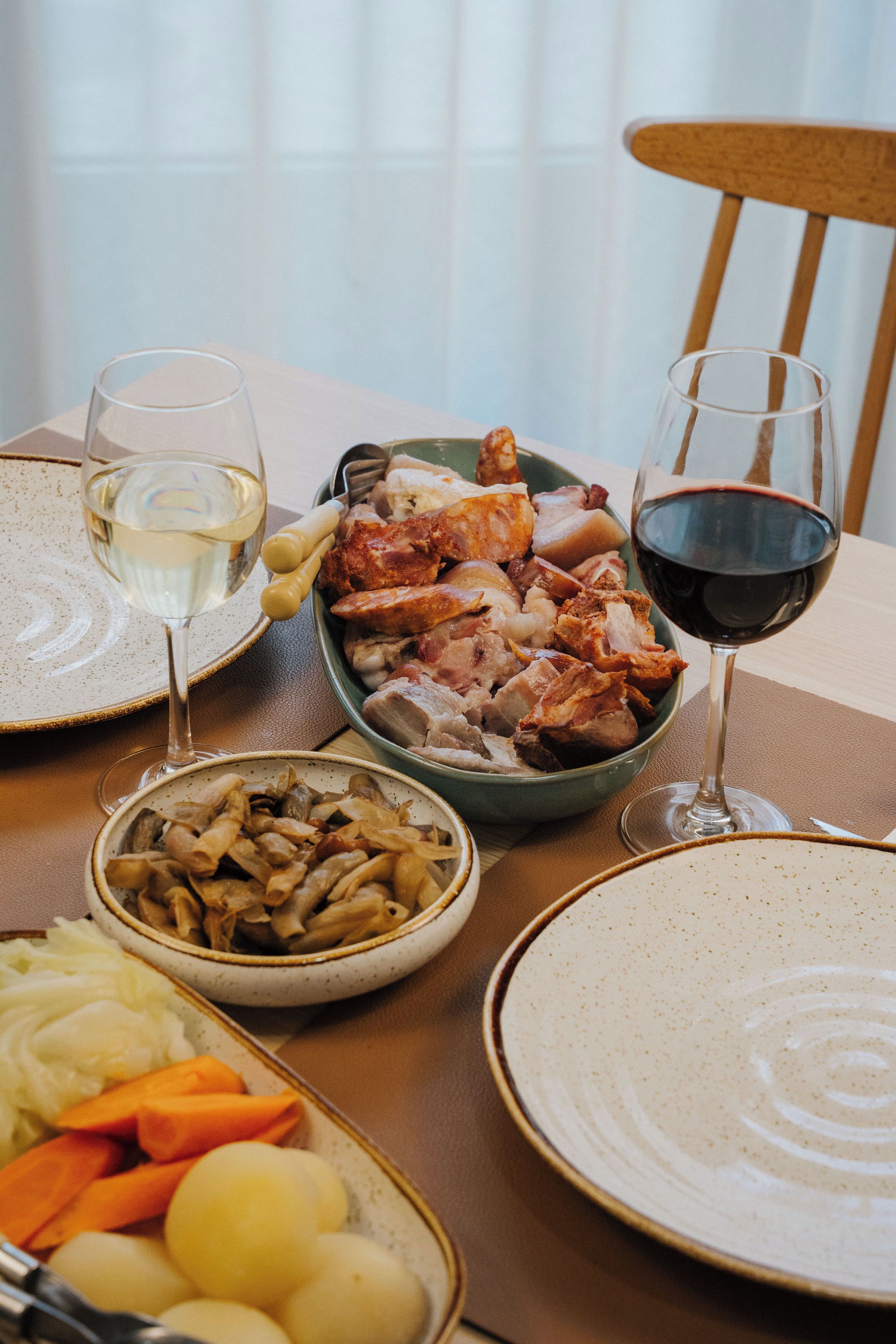Une table à manger avec des assiettes de nourriture, deux verres de vin et un bol de pâtes.