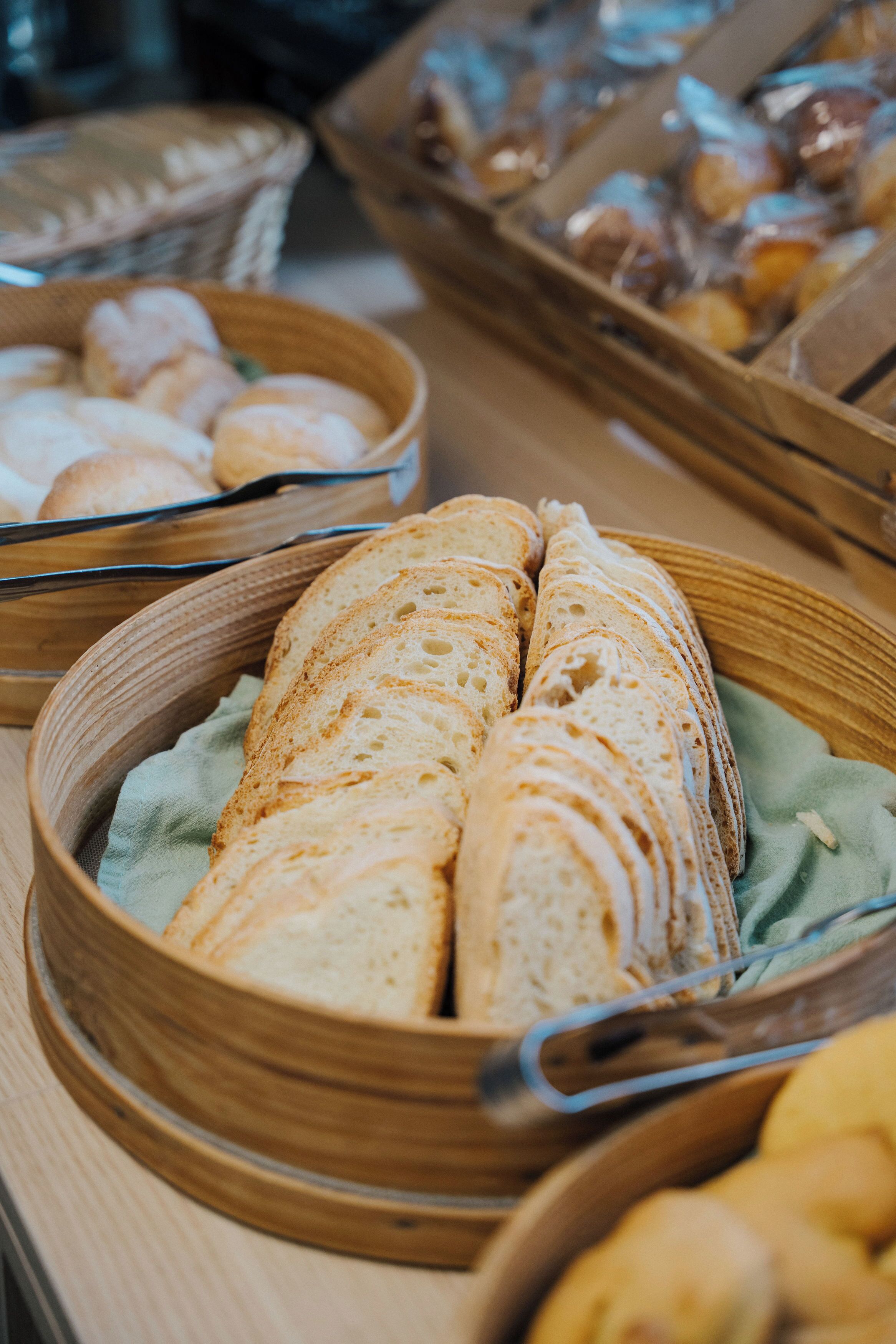 Een buffet met verschillende soorten brood en gebak, gepresenteerd in houten manden.