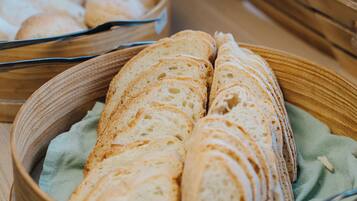 Een buffet met verschillende soorten brood en gebak, gepresenteerd in houten manden.