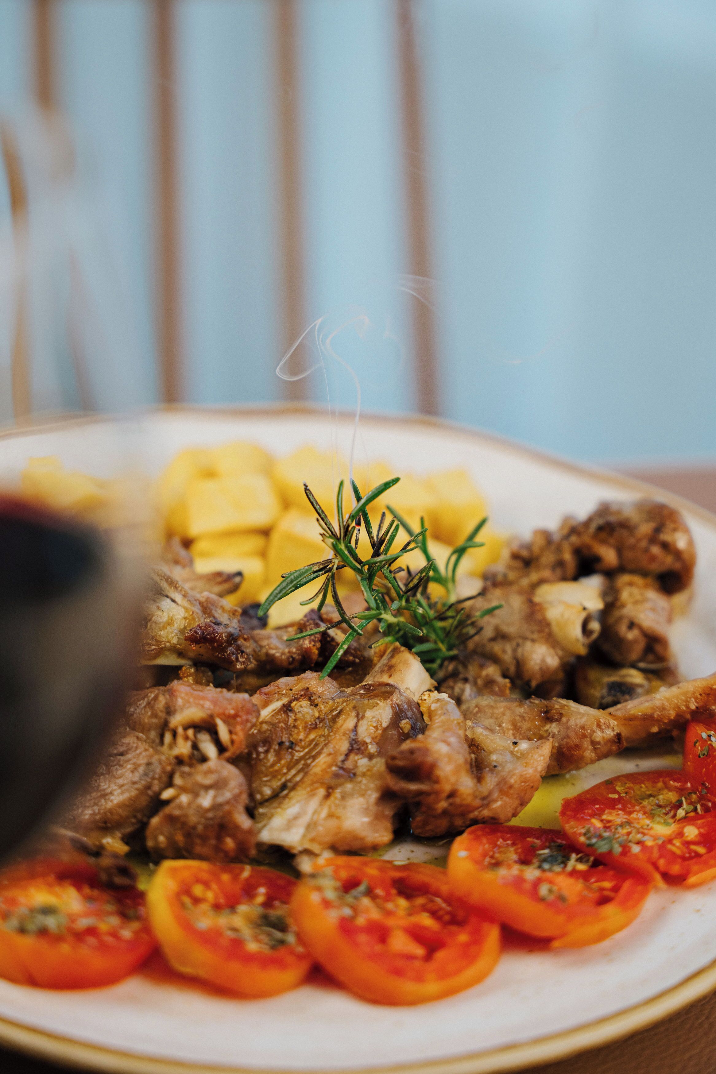 Une assiette de viande rôtie, de pommes de terre et de tomates.