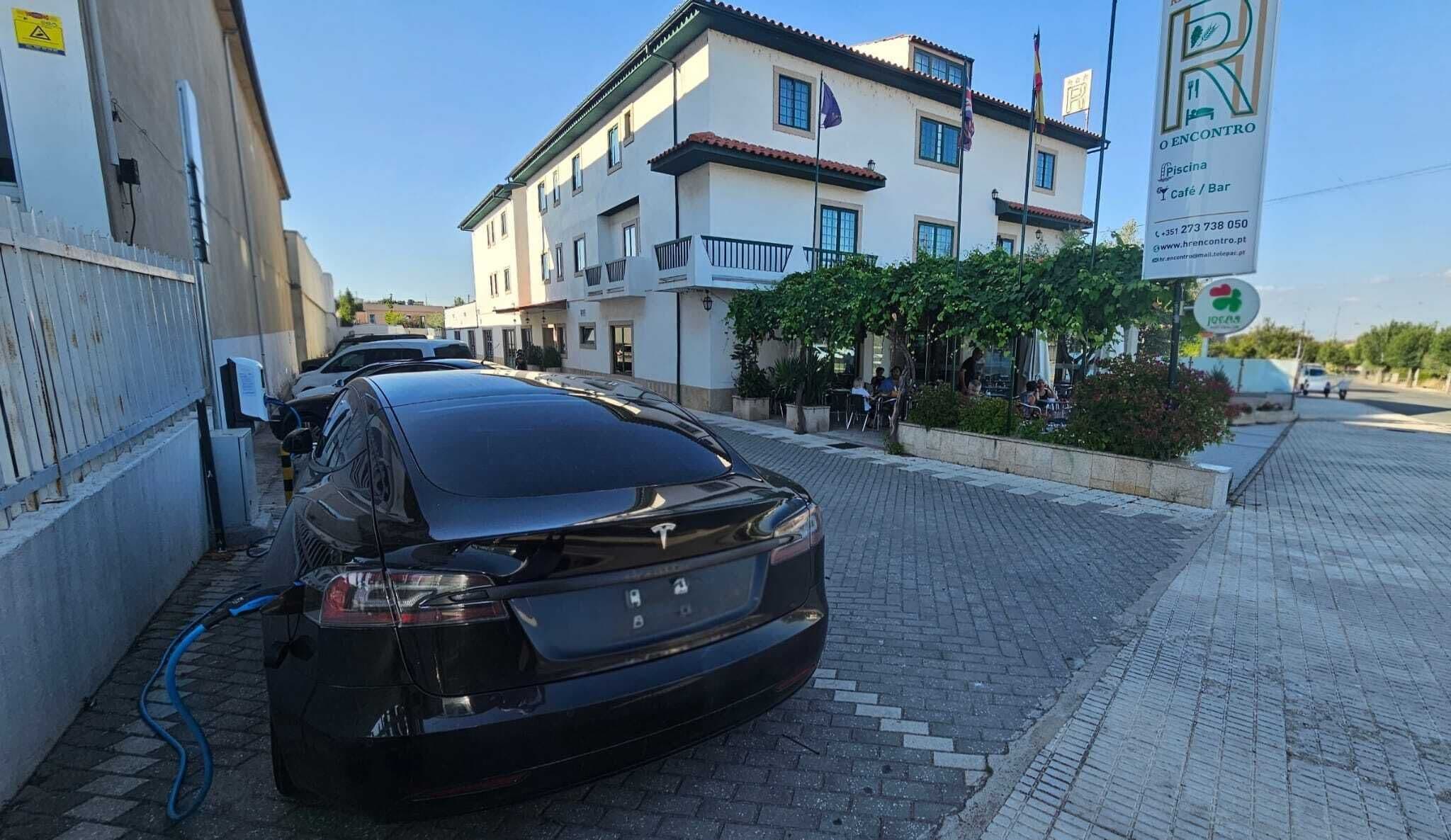 En svart bil parkerad framför en byggnad med en skylt som visar att det är ett café/en bar.