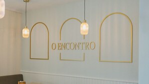 A dining area with tables and chairs, a bench, and a wall with the text "O ENCONTRO". - Hotel O Encontro (Miranda do Douro)