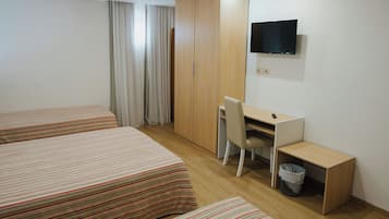 A hotel room with two beds, a desk, a chair, a TV, and a wardrobe.