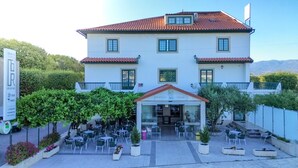 A two-story building with a cafe and restaurant on the ground floor, surrounded by outdoor seating and greenery. - Hotel O Encontro (Miranda do Douro)