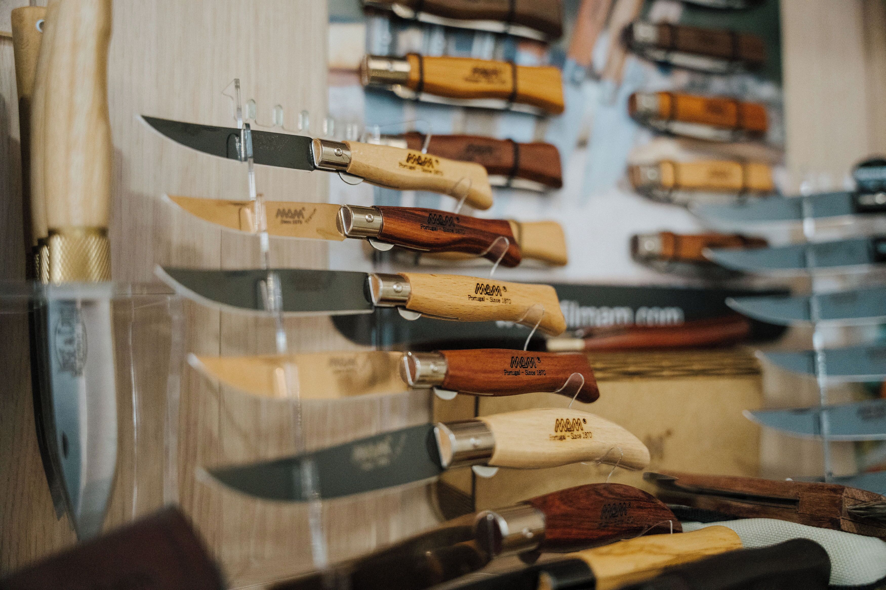 A display of knives with wooden handles and metal blades, arranged on a wall.