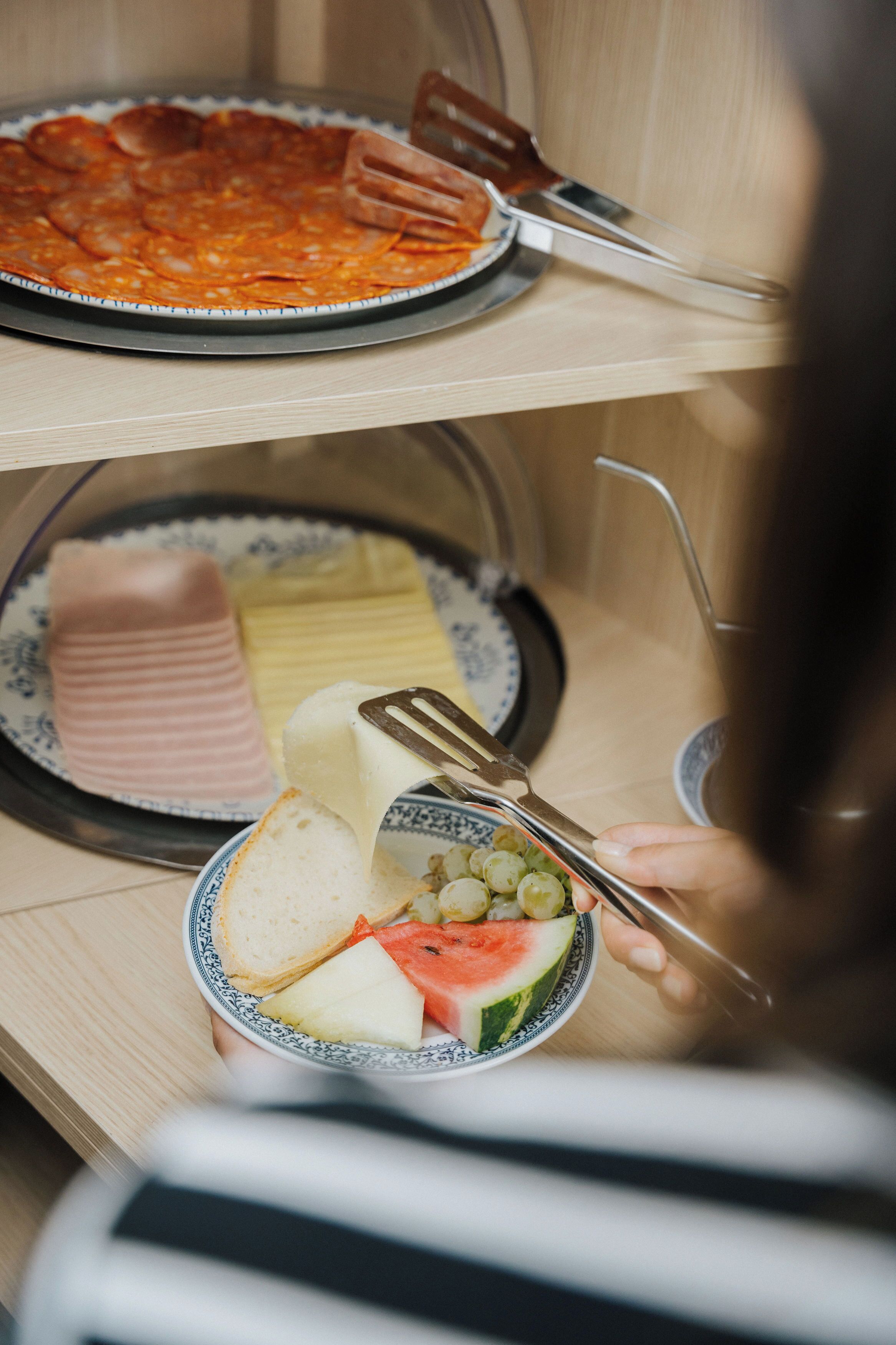 Un comedor con un plato de carne en rodajas, un bol de fruta y una tabla de queso.