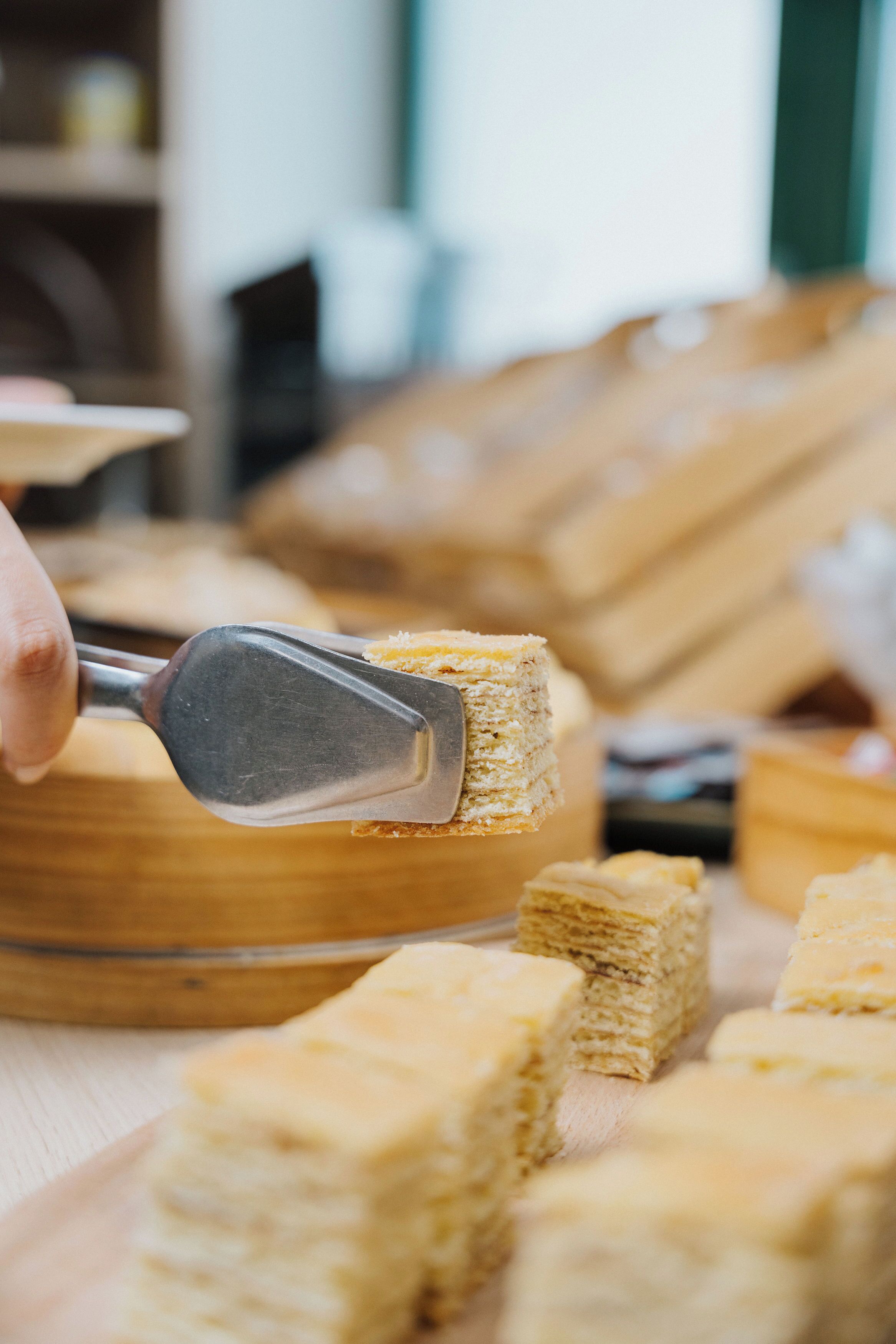 A close-up of a person using a tool to cut a layered pastry.