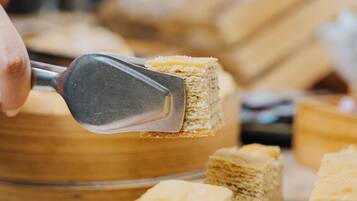 A close-up of a person using a tool to cut a layered pastry.