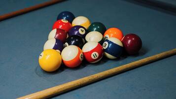 A pool table with a set of billiard balls and two pool cues.