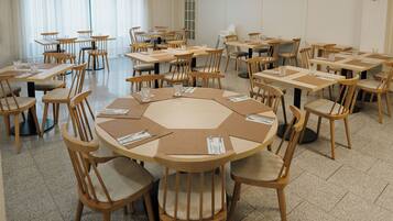 Un salón de conferencias con varias mesas y sillas, dispuestas en forma de U.