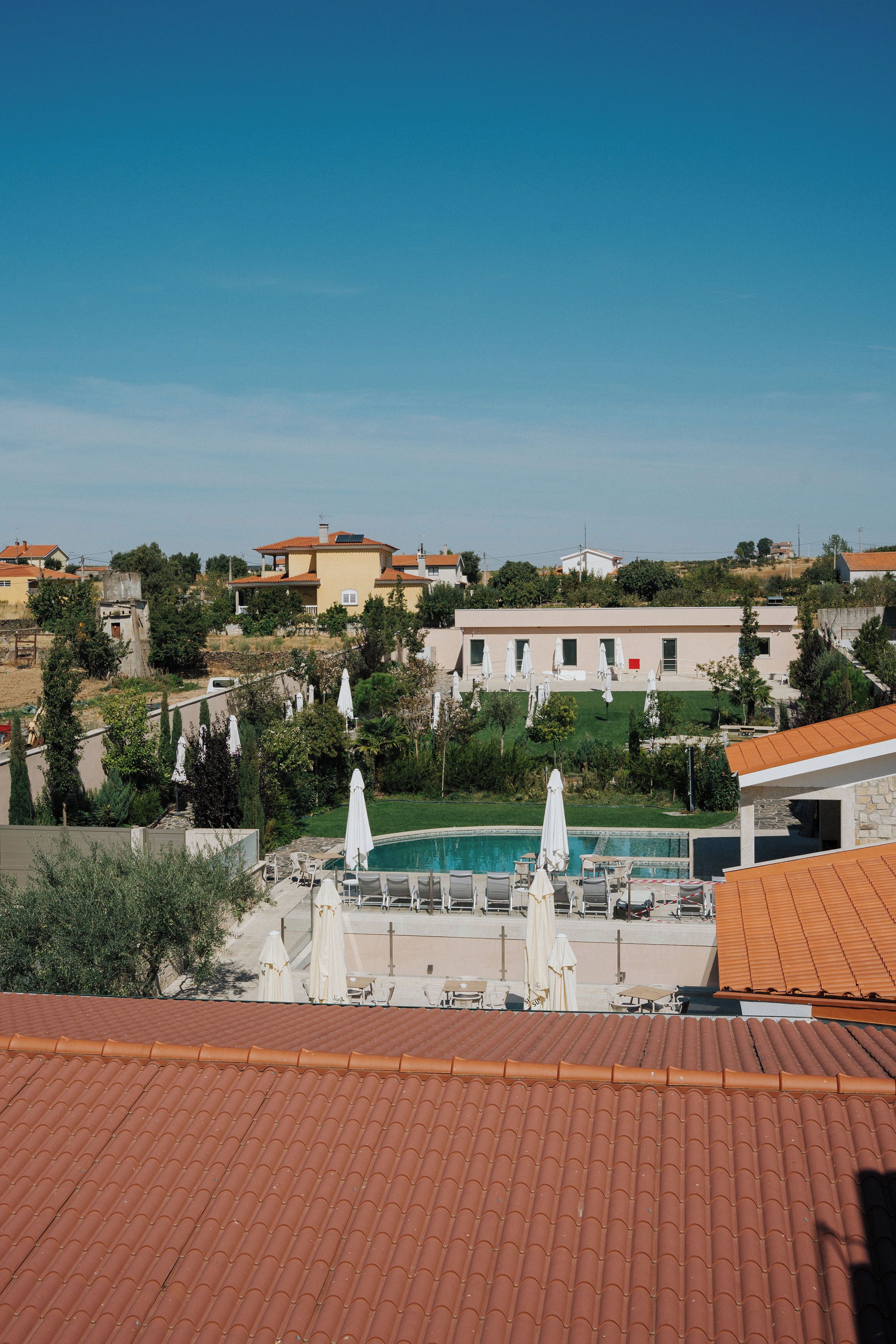 A residential area with a swimming pool, outdoor furniture, and a view of neighboring houses.