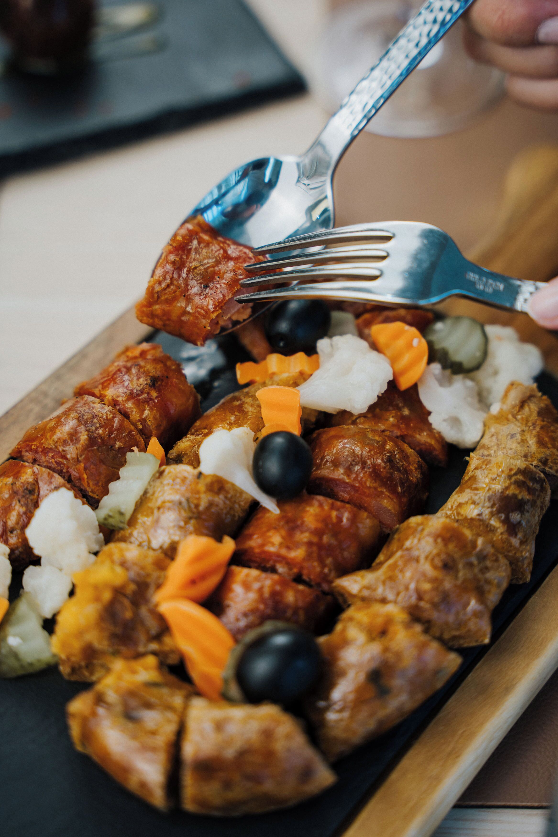 A platter of assorted meats and vegetables on a wooden board.