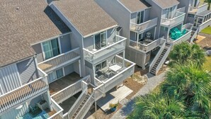 Un immeuble résidentiel à plusieurs étages doté de balcons, d’un espace extérieur aménagé pour s’asseoir et d’une piscine.