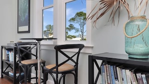 A room with a bookshelf, two chairs, a table, and a window with a view of trees. - So close to the pool! Beach Views, Multiple Decks, Gated Community. ~Brise Del M (Cape San Blas)