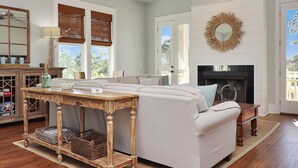 A living room with a sofa, a wooden table, a fireplace, and a large mirror. - So close to the pool! Beach Views, Multiple Decks, Gated Community. ~Brise Del M (Cape San Blas)
