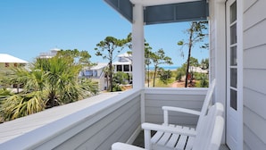 A white porch with a bench, overlooking a residential area with trees and a clear blue sky. - So close to the pool! Beach Views, Multiple Decks, Gated Community. ~Brise Del M (Cape San Blas)