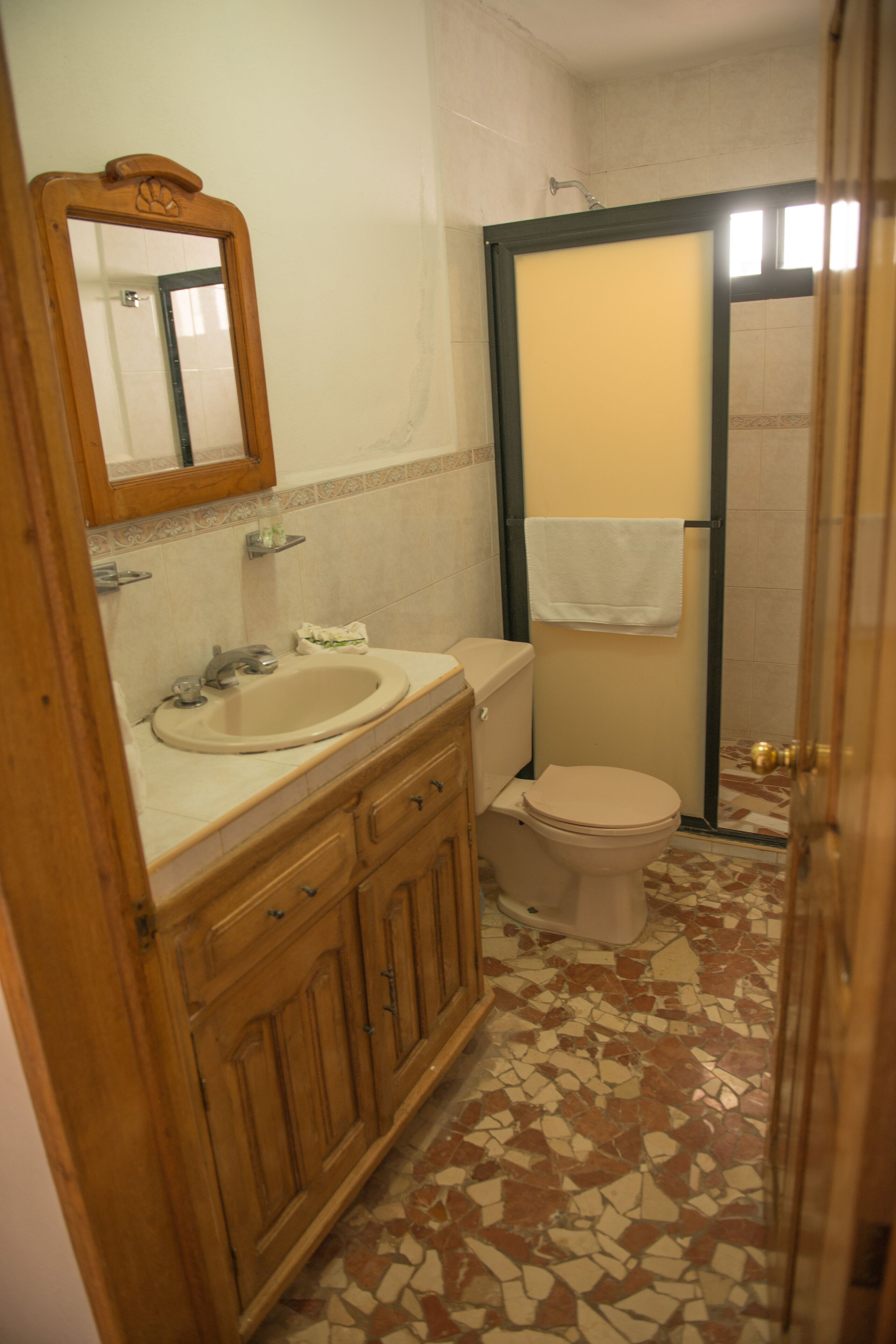 Une salle de bain équipée d’un lavabo, d’un miroir, de toilettes et d’un espace douche.
