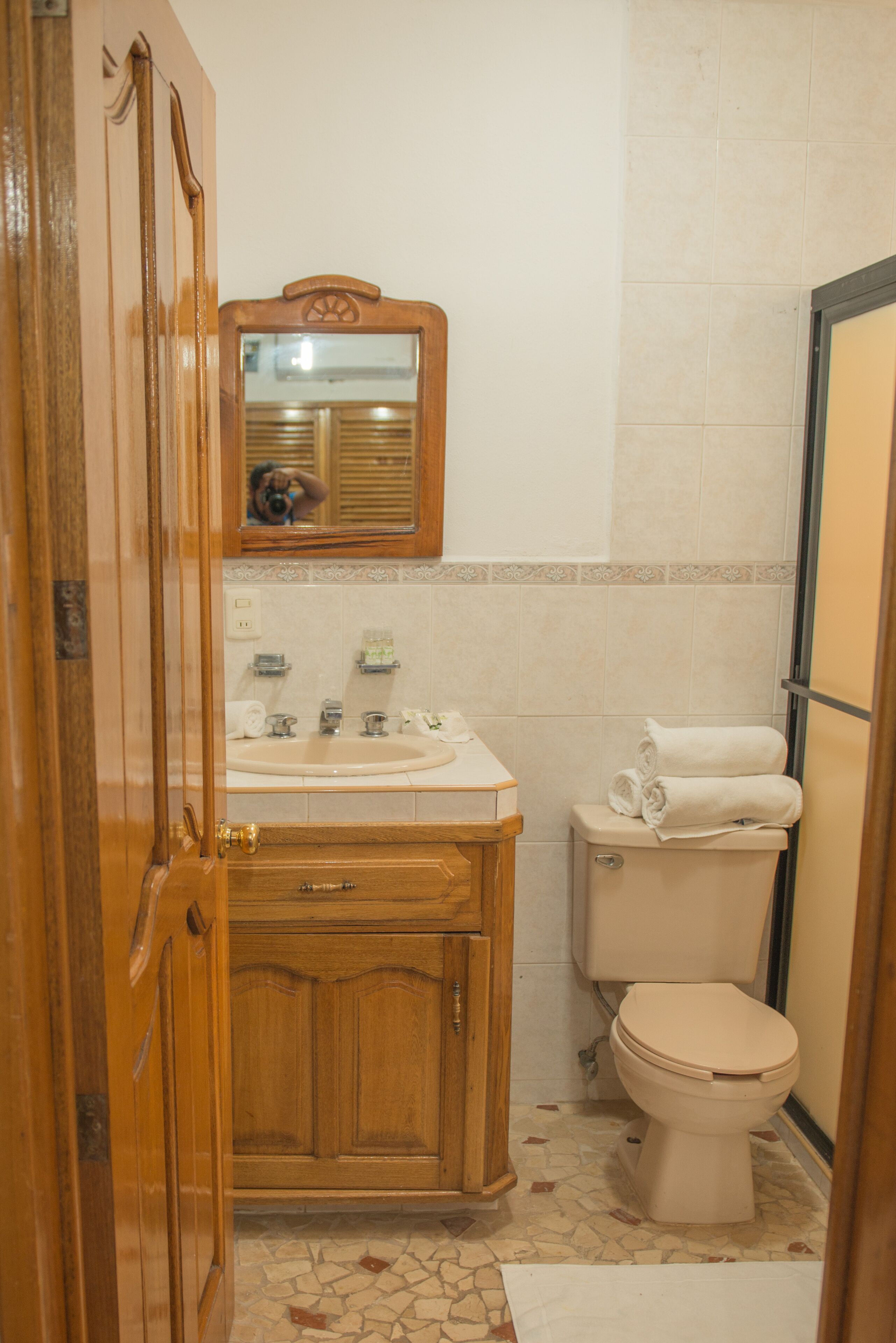Un baño con tocador de madera, lavamanos, inodoro y espejo.