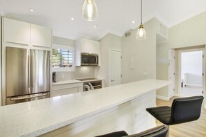 Una cocina moderna con electrodomésticos de acero inoxidable, una isla grande e iluminación colgante.