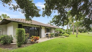 Une maison de plain-pied avec un toit en tuiles, une terrasse couverte et une pelouse bien entretenue.