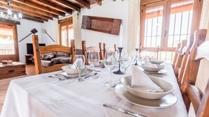 A dining table set for a meal with white tablecloth, plates, glasses, and cutlery.