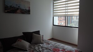 Un dormitorio con cama, una ventana con persianas y un cuadro en la pared.