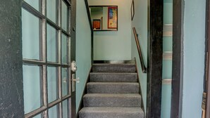 A staircase with carpeted steps leading to a landing with a door and a poster on the wall. - Your own historic estate in the heart of Old Louisville! NEAR IT All!! (Louisville)