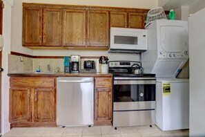 Une cuisine dotée de meubles en bois, d’un réfrigérateur en acier inoxydable, d’un four à micro-ondes, d’une machine à café, d’un grille-pain et d’une cuisinière.