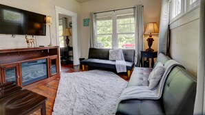 A living room with a sofa, a television, a fireplace, and a window with curtains. - Your own historic estate in the heart of Old Louisville! NEAR IT All!! (Louisville)