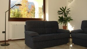 A living room with a large window, a floor lamp, a potted plant, and two sofas. - B&B Carunei (Poggiridenti)